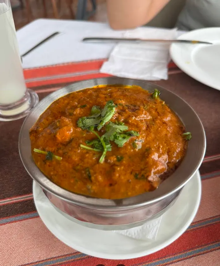 A steel bowl of rich, garnished curry