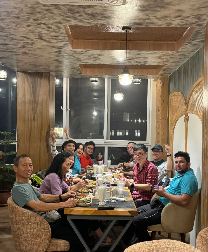 A large group sharing a long table on the rooftop at night