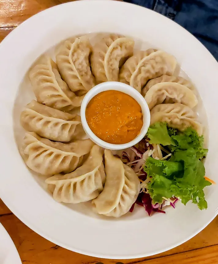 A plate of steamed momo with achar and fresh salad