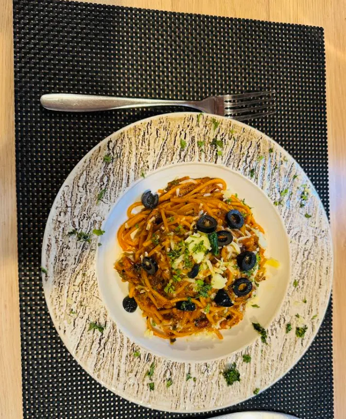 Penne pasta with olives, herbs and parmesan, seen from above